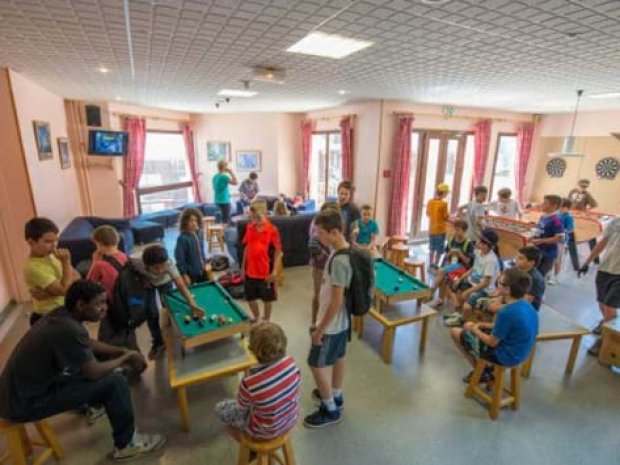 Enfants en colonie de vacances jouant dans la salle d'activité du centre de vacances à la montagne