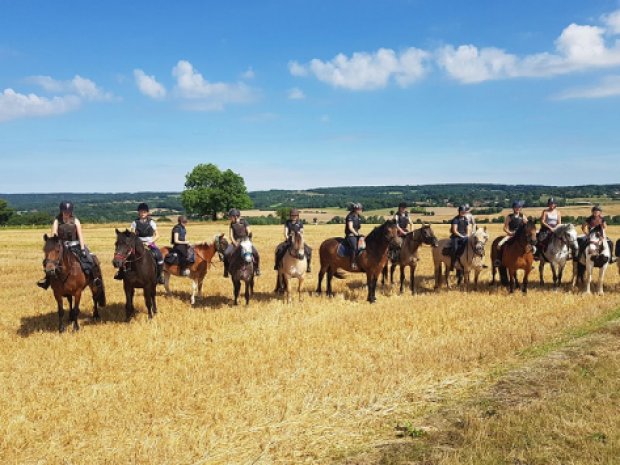 Vue sur un champs avec tous les cavaliers à cheval lors d'une colo de vacances