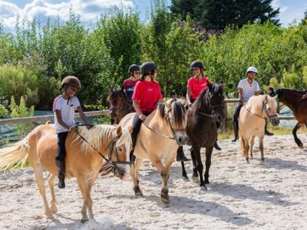 Vue sur des jeunes en colo de vacances qui sont à cheval au domaine de l'esperance