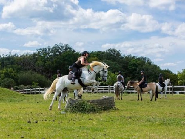 Cavalier qui franchit un obstacle à cheval lors d'une colo de vacances au domaine de l'esperance 